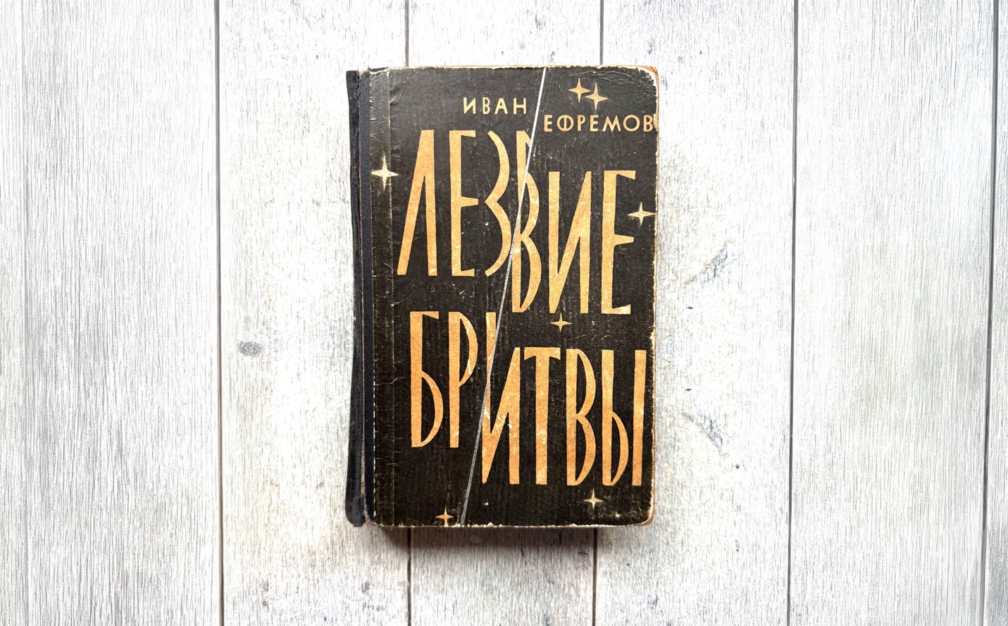 Потрёпанная обложка книги Ивана Ефремова «Лезвие бритвы» на фоне деревянных досок